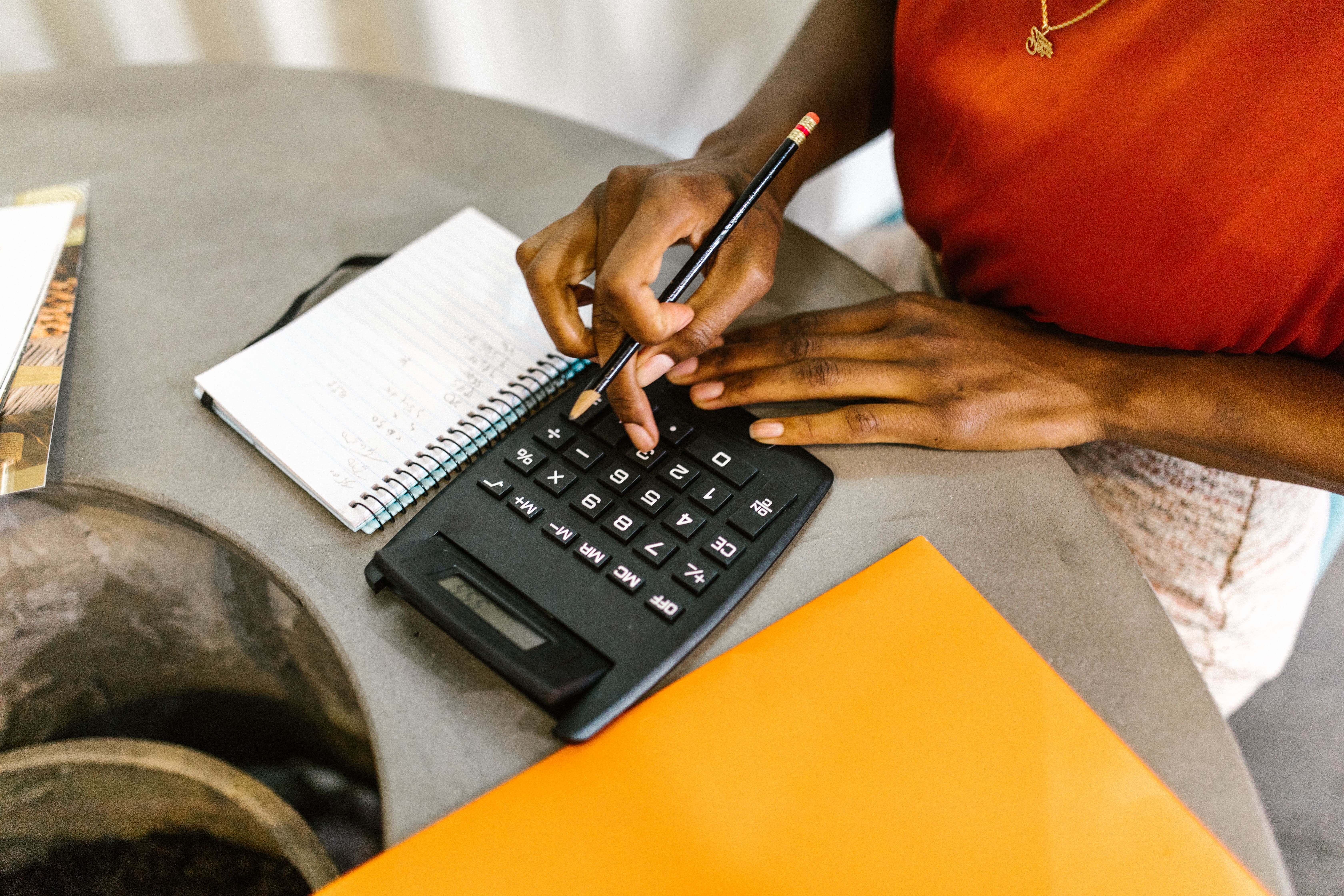 woman using a calculator with a notepad on the side